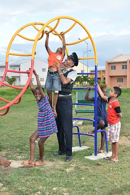A TTPS officer playing with children at a community park